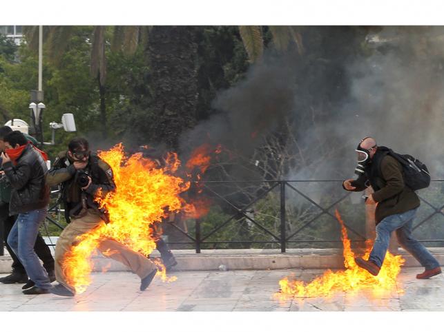 Fotoreporter w płomieniach podczas starć manifestantów z policją. Protest przeciwko cięciom budżetowym. Ateny, Grecja, 23 lutego 2011